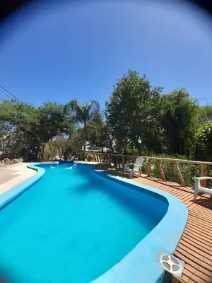 a pool with blue water and a wooden deck at Complejo de Cabañas Estancia Del Águila in Mina Clavero