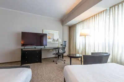 a hotel room with two beds and a desk with a television at Quinto Centenario Hotel in Cordoba