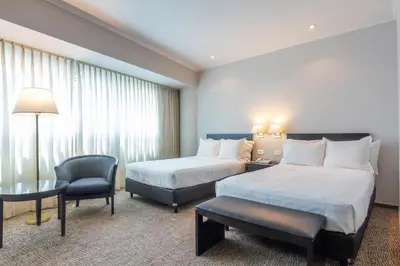 a hotel room with two beds and a chair at Quinto Centenario Hotel in Cordoba