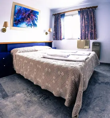 a bedroom with a bed with a blanket on it at Apart Hotel Magali in Cordoba