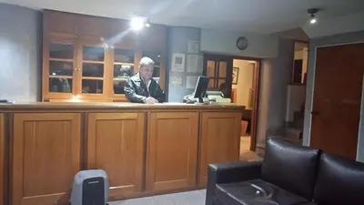 a man standing at a counter with a computer at Apart Hotel Magali in Cordoba