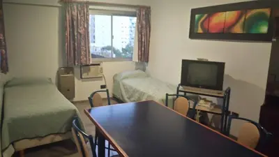 a room with two beds and a table and a tv at Apart Hotel Magali in Cordoba