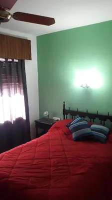 a bedroom with a red bed with red sheets and blue pillows at Residencial Ariand in Santa Rosa de Calamuchita