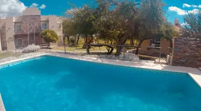a large blue swimming pool in front of a building at Altos Serranos Apart in Merlo