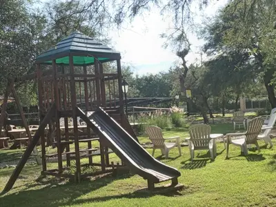 a playground with a slide and chairs in a park at Altos Serranos Apart in Merlo