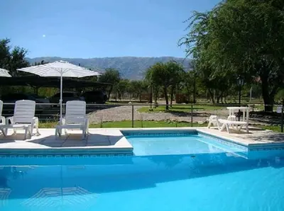 a swimming pool with two chairs and an umbrella at Altos Serranos Apart in Merlo
