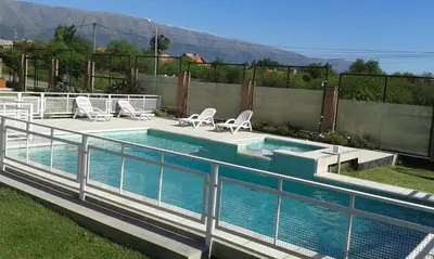 a swimming pool with chairs and a fence at Complejo Abuela Lety in Merlo