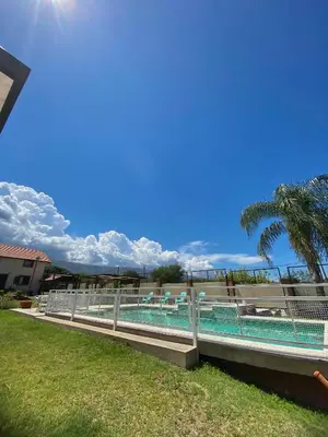 a swimming pool with a fence and a palm tree at Complejo Abuela Lety in Merlo