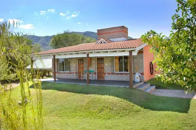 a small house with a grass yard in front of it at Posada Jardin del Cerro in Santa Rosa de Calamuchita