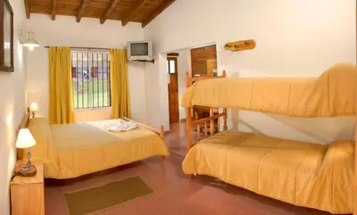 a bedroom with two bunk beds and a television at Posada Jardin del Cerro in Santa Rosa de Calamuchita