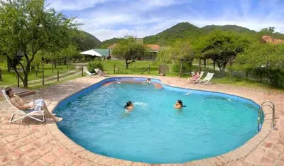 three people in a swimming pool in a yard at Posada Jardin del Cerro in Santa Rosa de Calamuchita