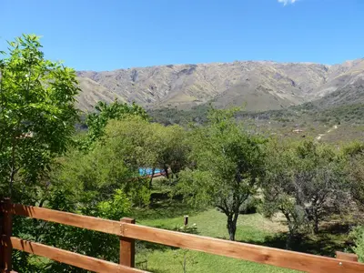 a fence with trees and mountains in the background at Cabañas de los Comechingones in Merlo