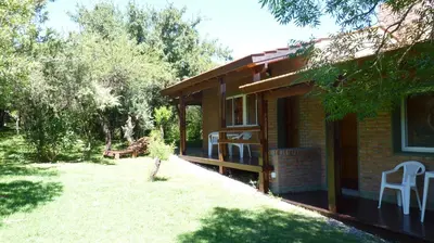 a house with a yard next to a building at Cabañas de los Comechingones in Merlo