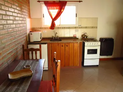 a small kitchen with a stove and a window at Cabañas de los Comechingones in Merlo