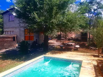 a swimming pool in front of a house with a tree at Cabaña Silvana in Bialet Massé