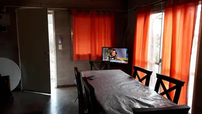 a dining room with a table and a tv and curtains at Cabaña Silvana in Bialet Massé