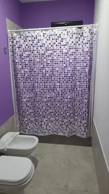 a bathroom with a toilet and a purple shower curtain at Casas del Champaquí in San Javier