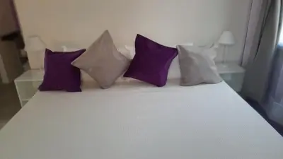 a bed with purple and white pillows on it at Casas del Champaquí in San Javier