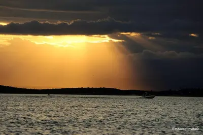a boat in the water with the sun setting at Altos del Tala Deptos - Cabañas in Embalse