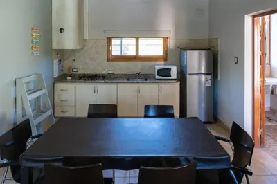 a kitchen with a table with chairs and a refrigerator at Portal de la Virgen in Villa General Belgrano