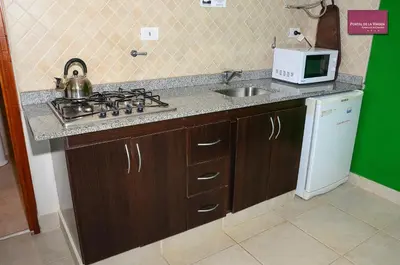 a kitchen with a sink and a stove and a microwave at Portal de la Virgen in Villa General Belgrano