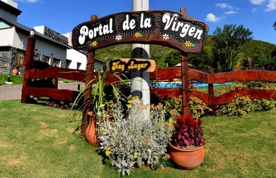 a sign for a restaurant with flowers in a yard at Portal de la Virgen in Villa General Belgrano