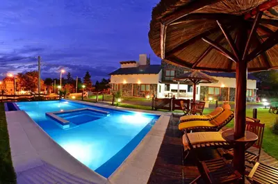 a swimming pool with chairs and an umbrella at Portal de la Virgen in Villa General Belgrano