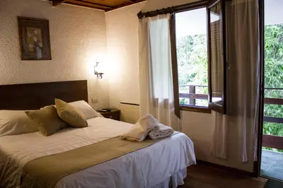 a bedroom with a bed and a large window at Solares Cumbrecita Hotel & Apart in La Cumbrecita