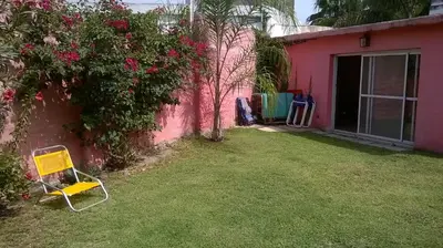 a yellow chair sitting in a yard next to a pink house at LF Departamentos in Cordoba