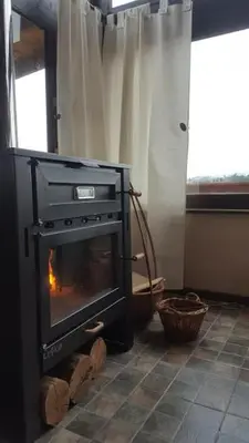 a stove in a room with a fireplace at Gran Cabaña en Villa Yacanto in Villa Yacanto