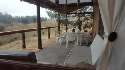 a porch of a house with a table and chairs at Gran Cabaña en Villa Yacanto in Villa Yacanto