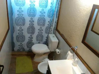 a bathroom with a toilet and a blue shower curtain at Gran Cabaña en Villa Yacanto in Villa Yacanto