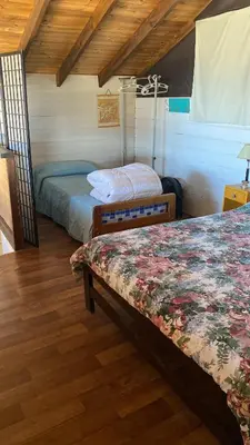 two beds in a room with wooden floors at Gran Cabaña en Villa Yacanto in Villa Yacanto