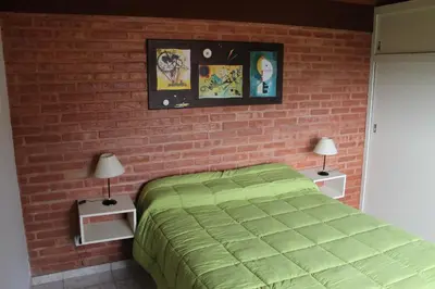 a bedroom with a brick wall with a bed and two lamps at Cabañas Pampa in Mina Clavero