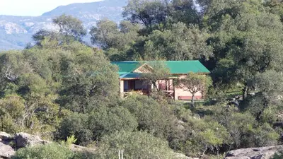 a house on the side of a hill with trees at Cabañas Pampa in Mina Clavero