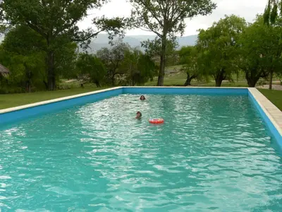 two people swimming in a blue swimming pool at Cabañas Pampa in Mina Clavero