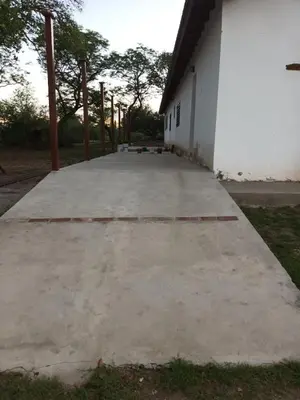 a large concrete sidewalk next to a white building at Posta Los Reartes in Los Reartes