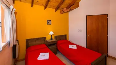 two beds in a room with yellow walls at Posta Los Reartes in Los Reartes