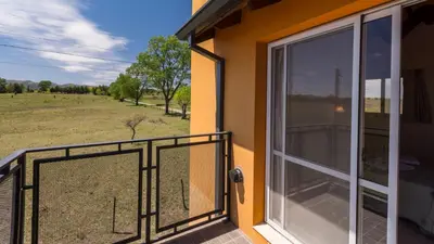 a balcony with a door and a view of a field at Posta Los Reartes in Los Reartes
