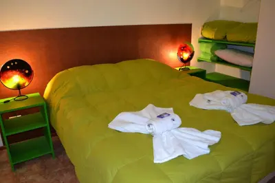 a bedroom with a green bed with towels on it at Posta Suites Apart - Los Reartes in Los Reartes
