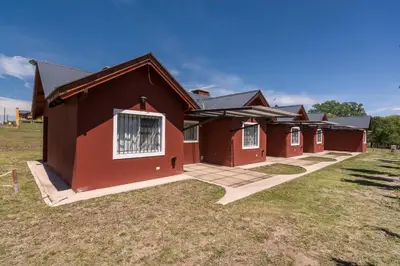 a group of red buildings in a field at Posta Suites Apart - Los Reartes in Los Reartes
