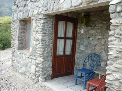a stone house with a blue chair and a door at Verde Niña Casas Serranas in Cortaderas