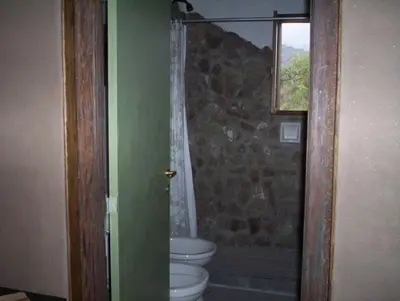 a bathroom with a toilet and a stone wall at Verde Niña Casas Serranas in Cortaderas
