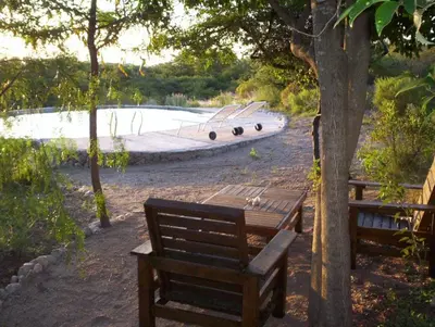 two wooden benches sitting in front of a pool at Verde Niña Casas Serranas in Cortaderas