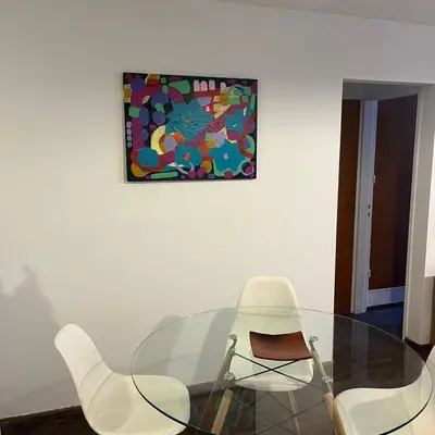 a glass table with white chairs and a painting on the wall at Edificio Torre Agora in Cordoba