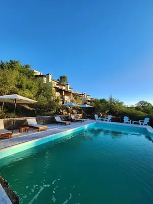 a large swimming pool with chairs and umbrellas at Terrazas de Piedra in Santa Rosa de Calamuchita