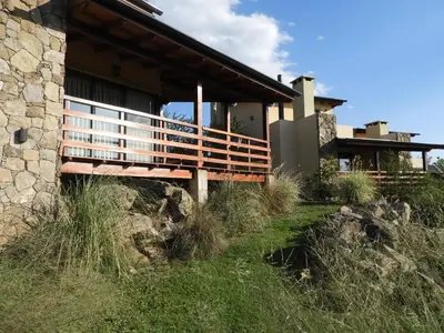 a house on a hill with a wooden deck at Terrazas de Piedra in Santa Rosa de Calamuchita