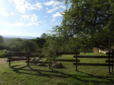 a wooden fence in a field with a tree at Terrazas de Piedra in Santa Rosa de Calamuchita