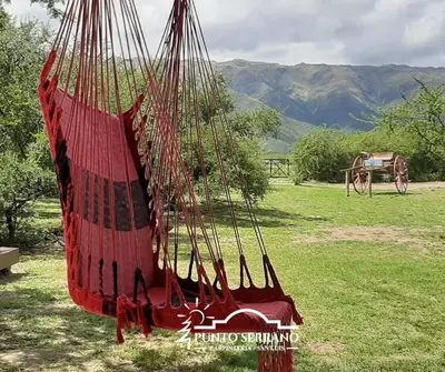 a red hammock in a field with mountains in the background at Punto Serrano in Carpintería