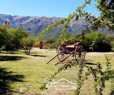 a cart sitting in a field with mountains in the background at Punto Serrano in Carpintería